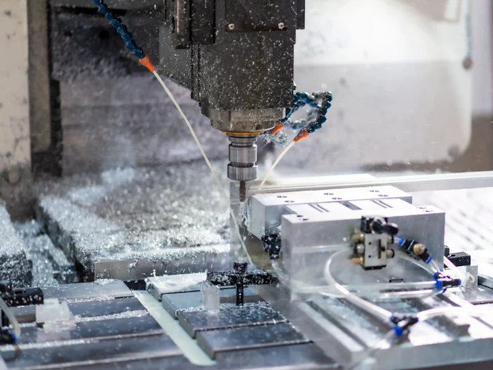 CNC machine cutting a steel block with coolant
