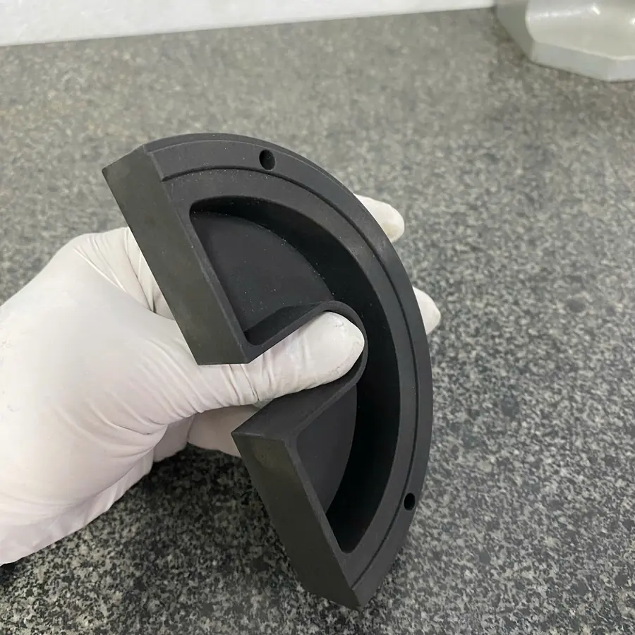 CNC milled black half-round cover with deep pocket and stepped rim, on a granite surface plate