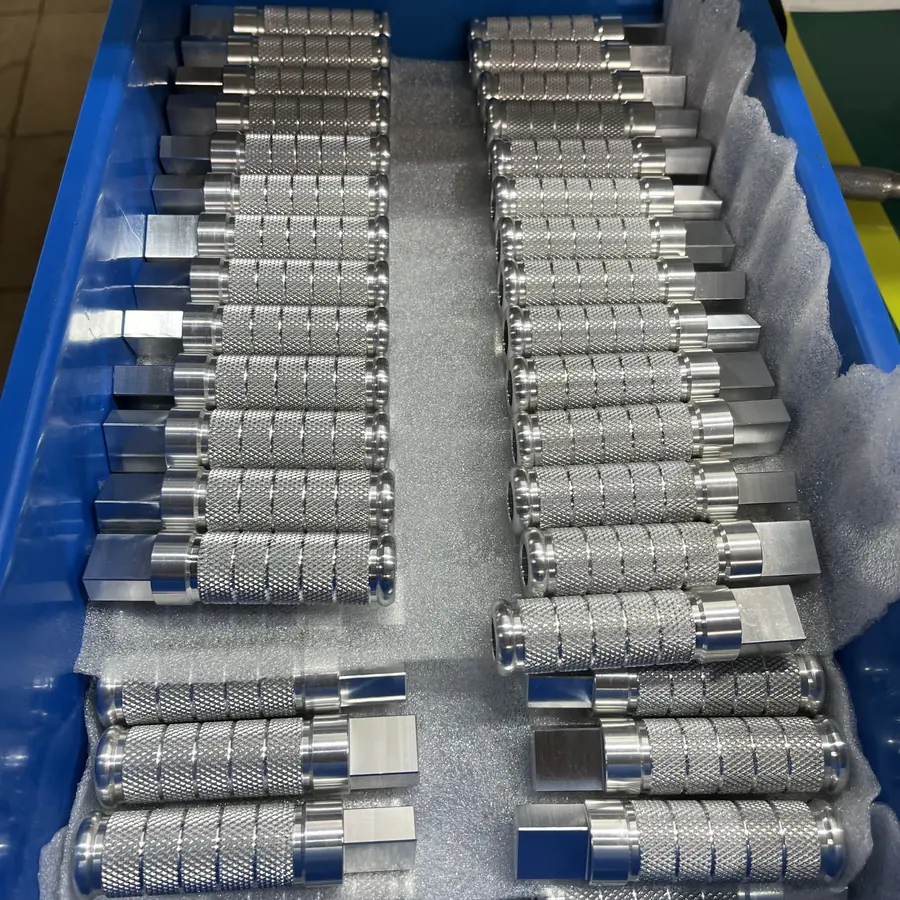 Rows of CNC turned knurled handles with grooves and a milled square end, laid on foam